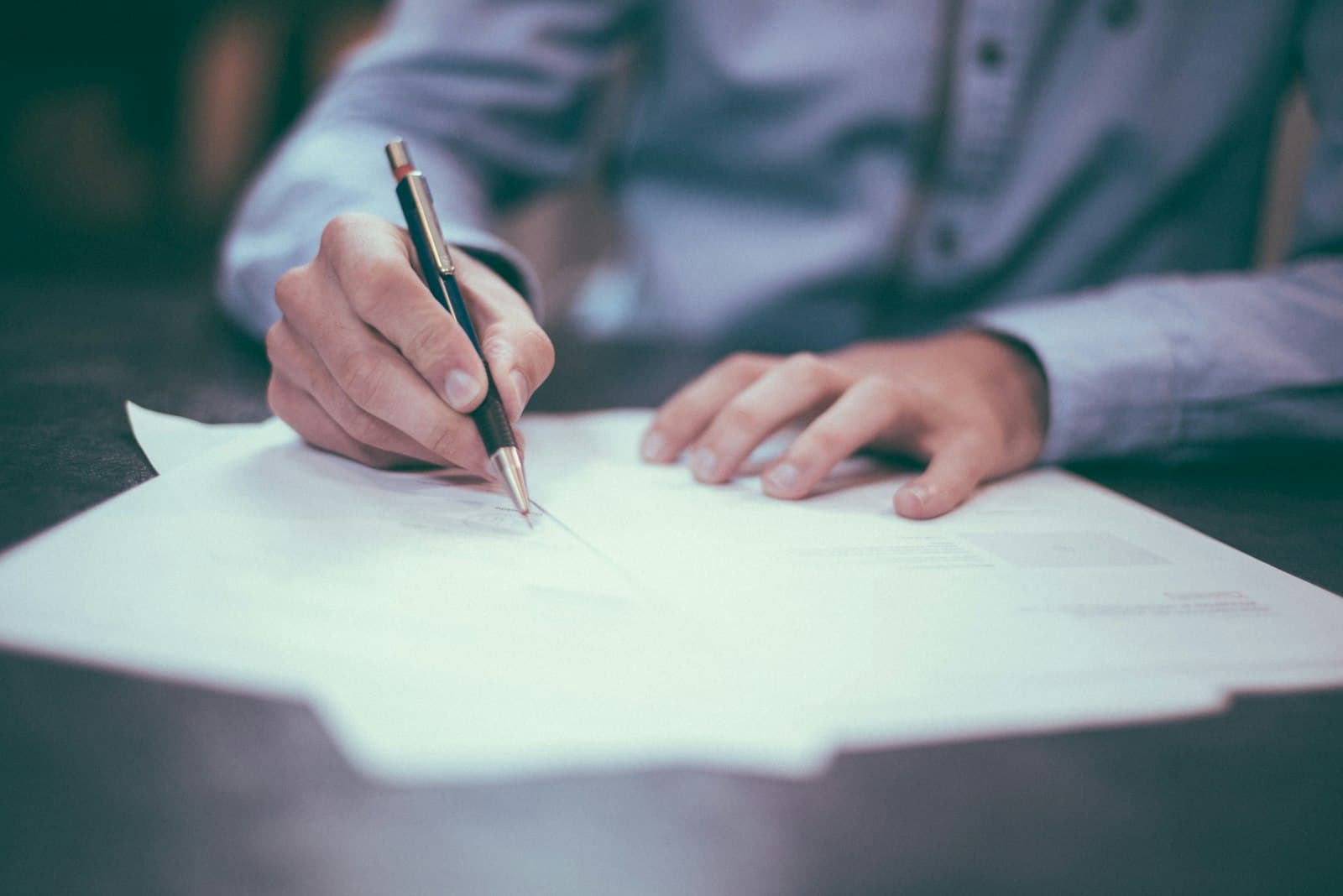 Signature d'un document à la main, sur un bureau